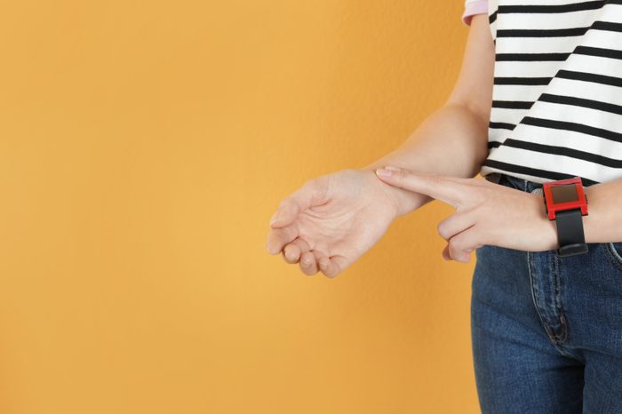 woman checking pulse yellow background