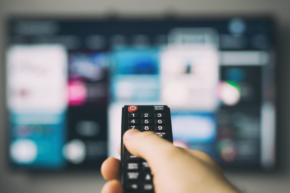 Male hand holding TV remote control.