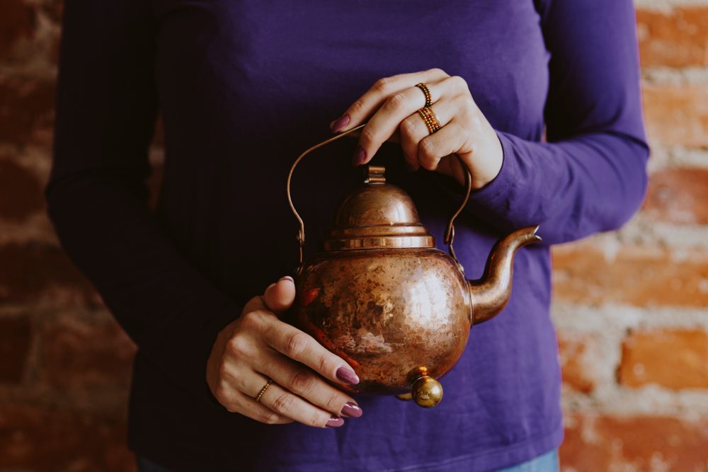 Women holding the small brown teapot