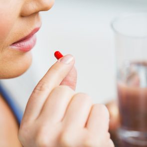 medicine, health care and people concept - close up of woman taking in pill