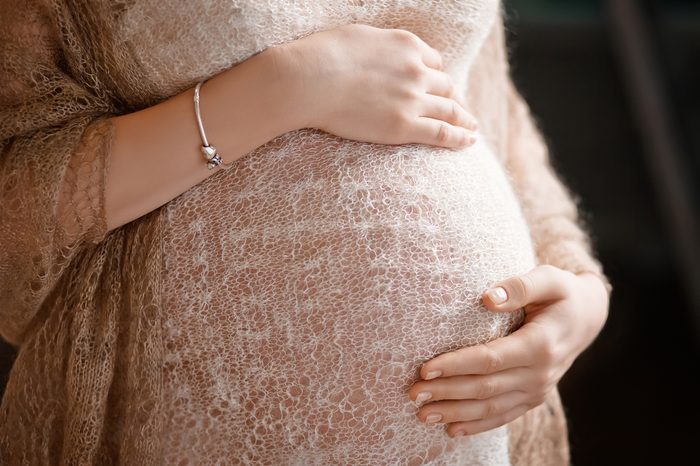 Close-up image of pregnant woman touching her belly with hands