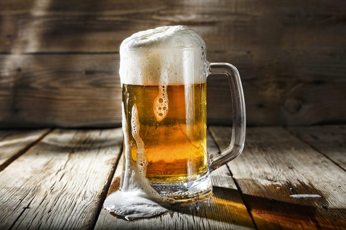 Mug of light beer pills with foam on a wooden table in a pub