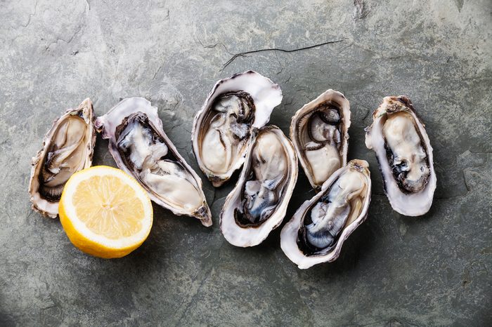 Opened Oysters on stone slate plate with lemon