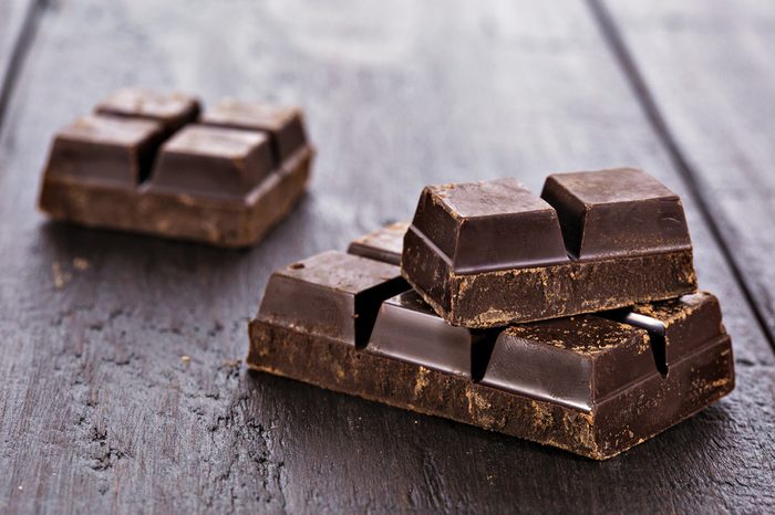 Close up of dark chocolate pieces on wooden table background.