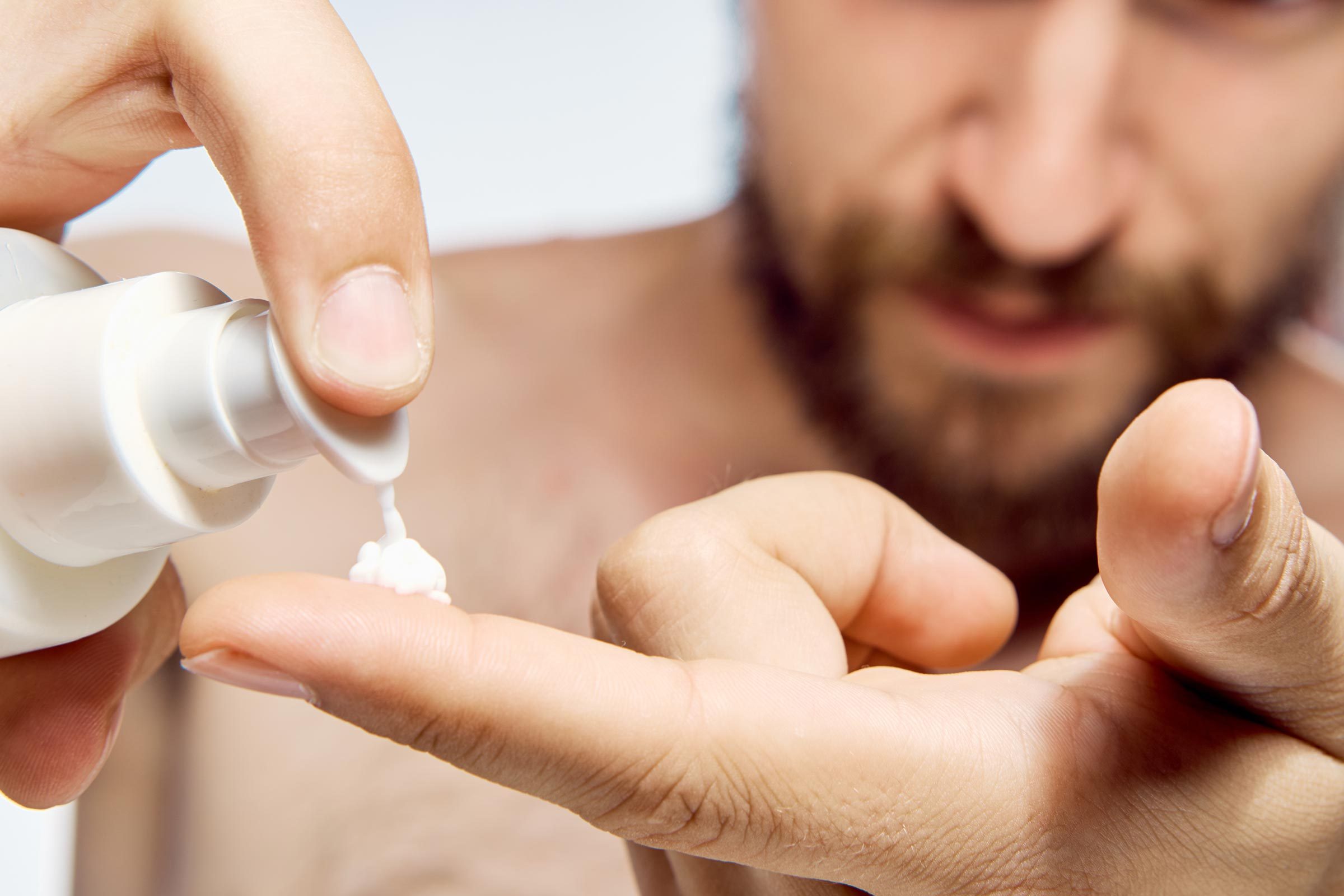 man pumping lotion onto his finger