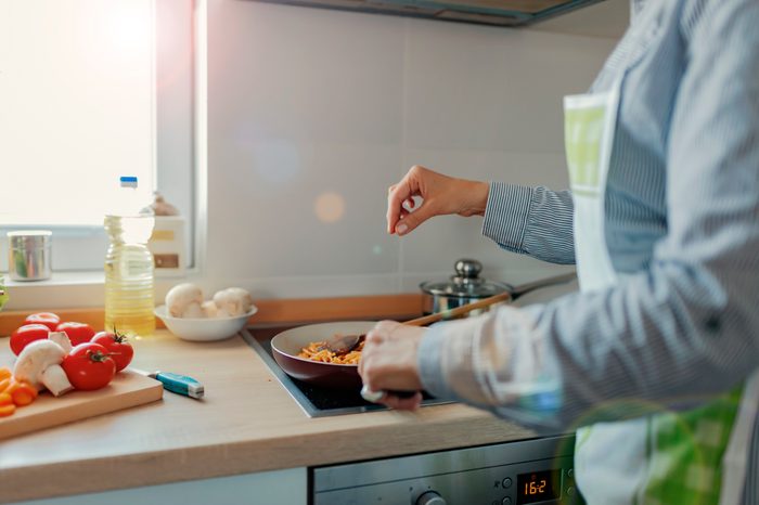 sprinkling salt from above onto food that is cooking on the stove