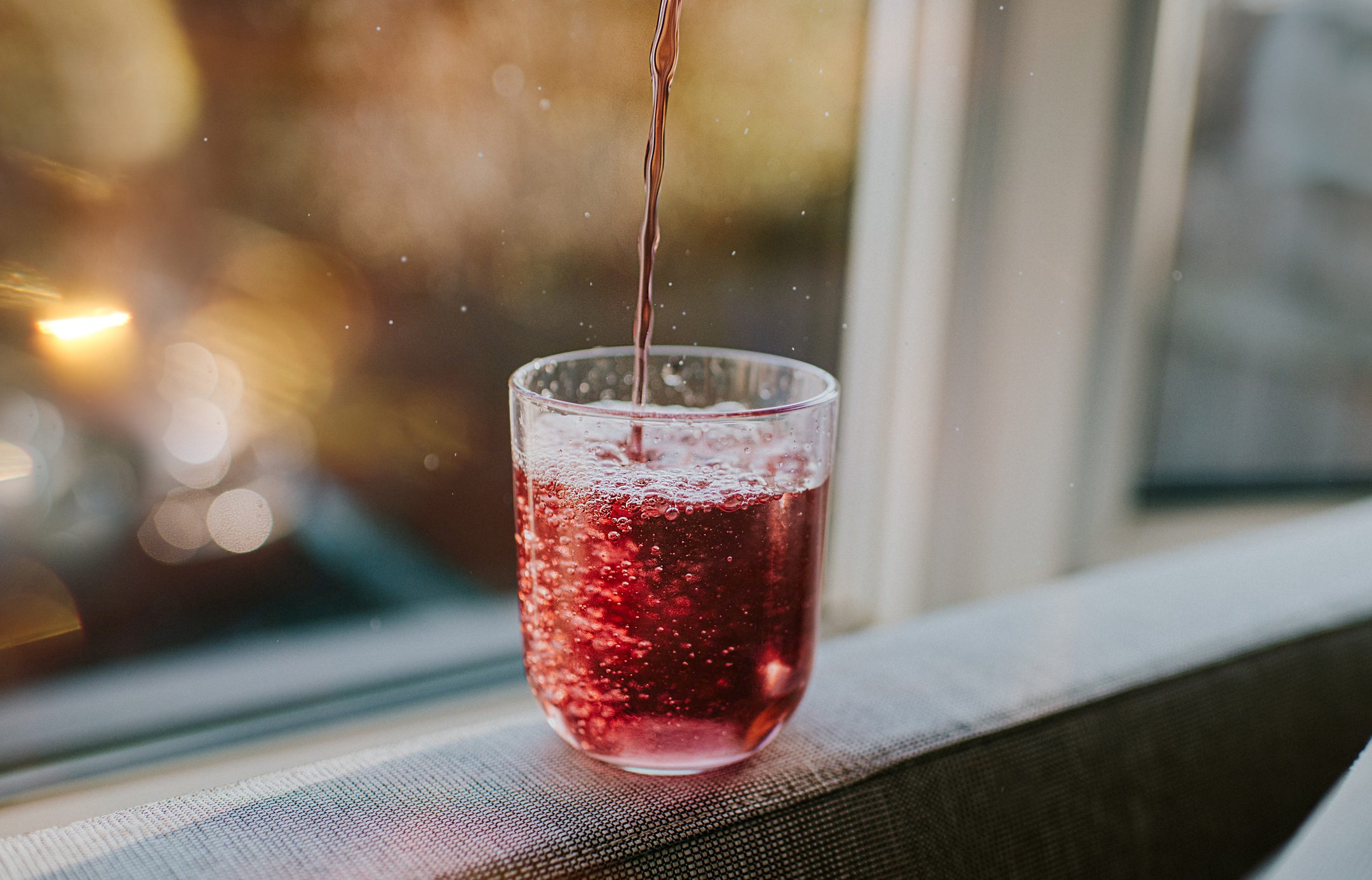 pouring glass of red soda