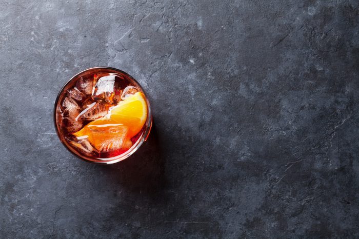 Negroni cocktail on dark stone table. Top view with space for your text