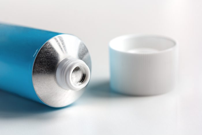 sealed tube of ointment on a white background with an open lid