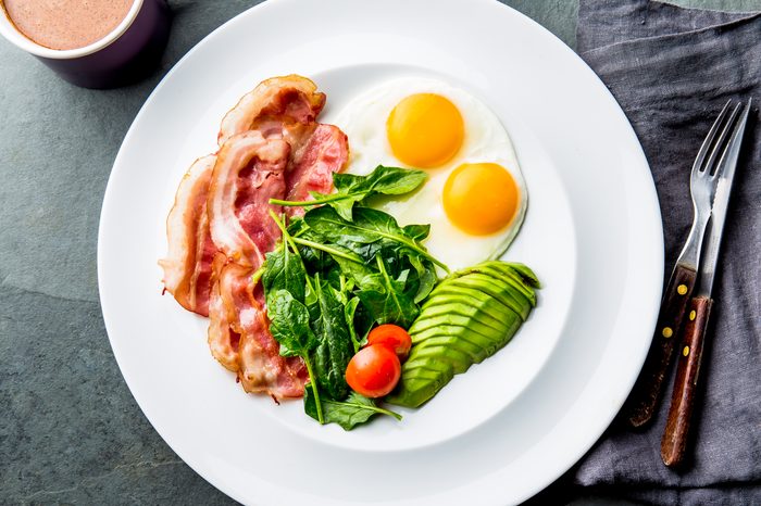 Ketogenic diet breakfast. fried egg, bacon and avocado, spinach and bulletproof coffee. Low carb high fat breakfast.