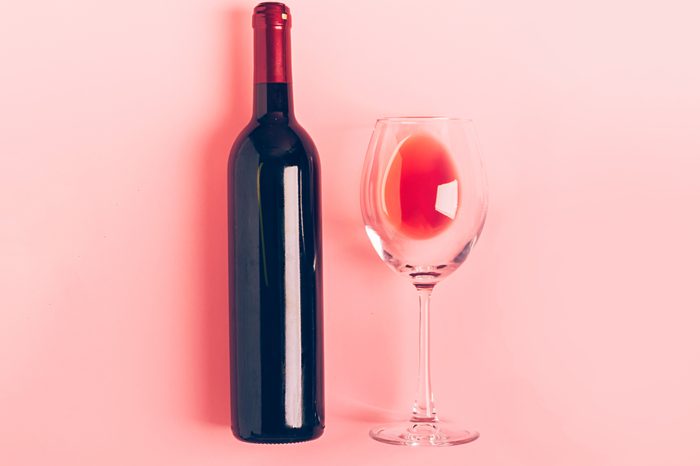 A bottle of wine an empty glass of a bunch of red grapes on a gentle pink background. Flat layout top view. Copy space. Minimalism. Horizontal frame; Shutterstock ID 1409701445; Job (TFH, TOH, RD, BNB, CWM, CM): -