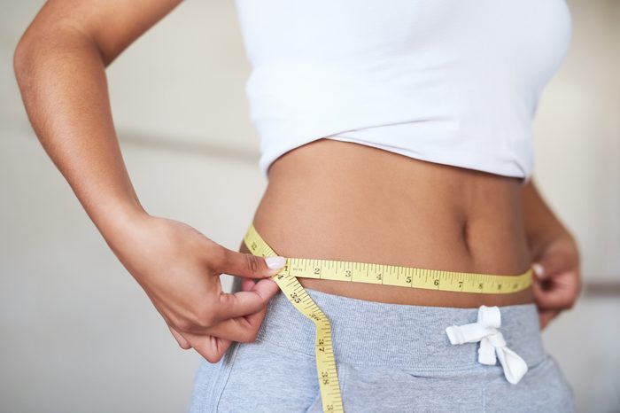 woman measuring her waist in the bathroom