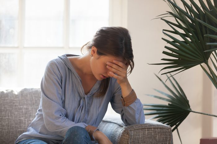 fatigued woman sitting on couch at home