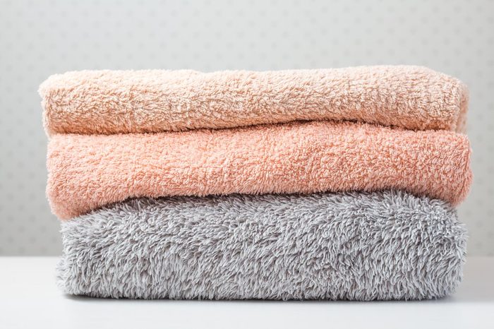 Bath towels of different colors in wicker basket on light background