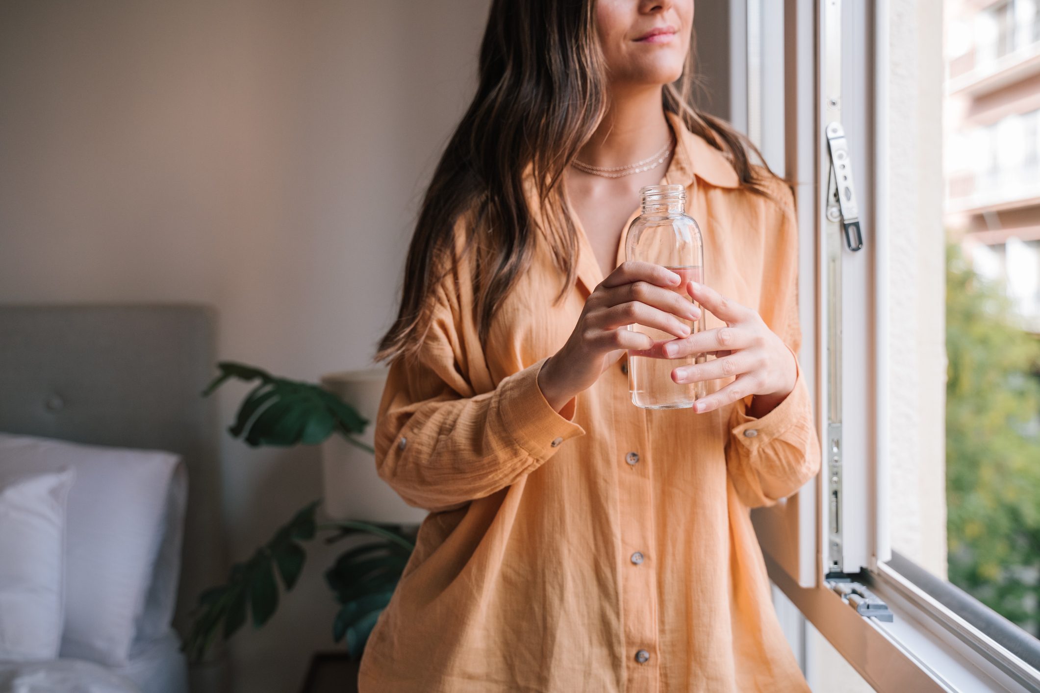 cropped shot of woman holding a glass of water inside home