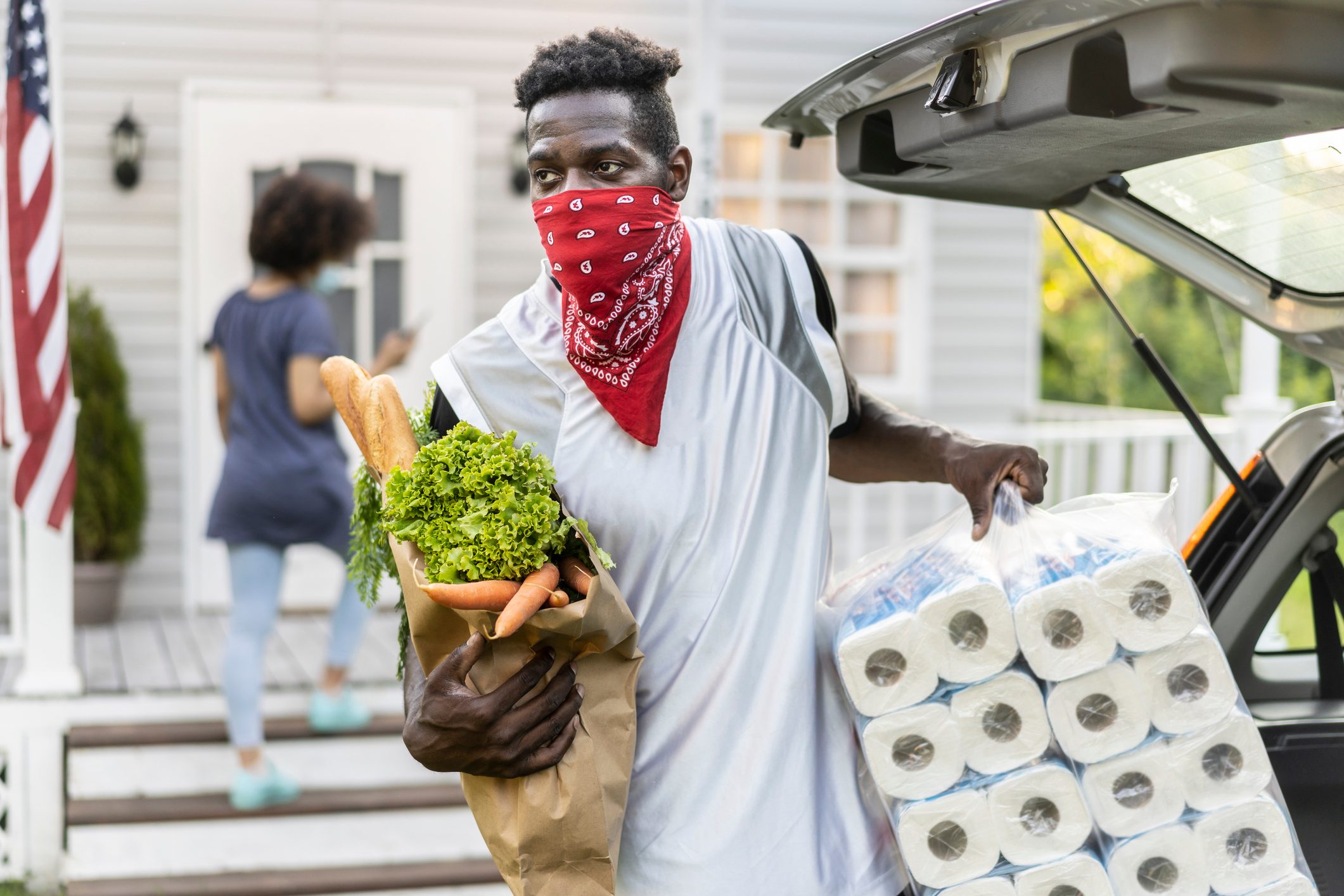 man wearing bandana as face mask carrying groceries