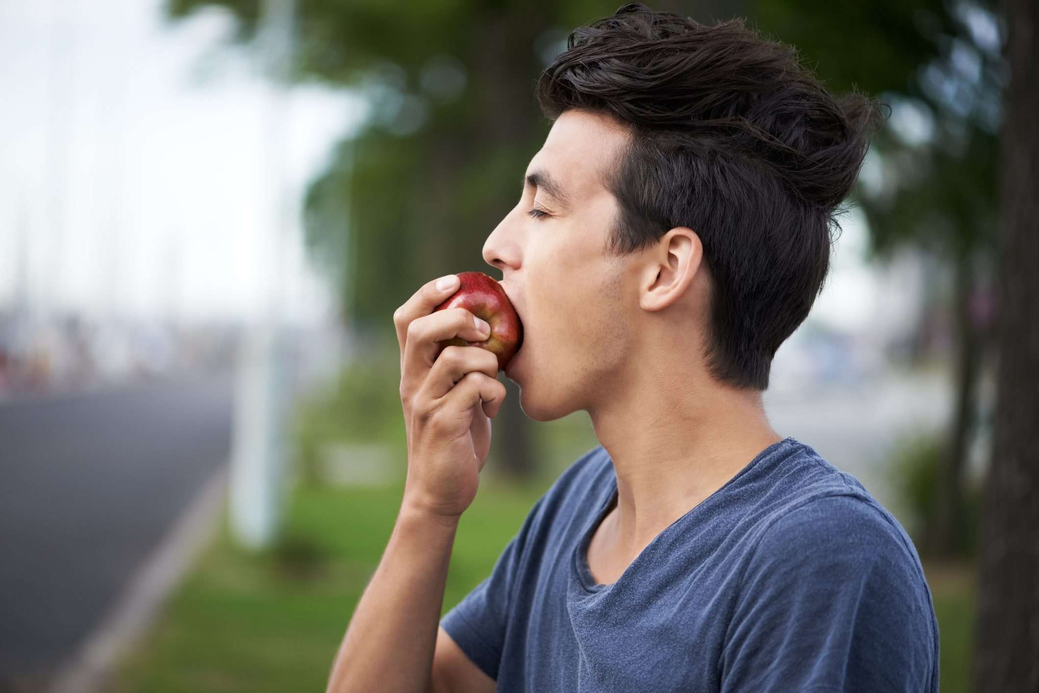 young man taking a bite into an apple