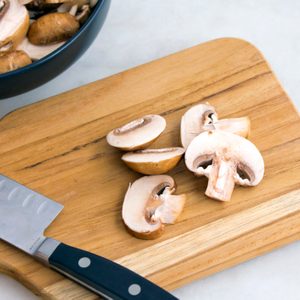 Slicing Cremini Mushrooms on a Wood Cutting Board