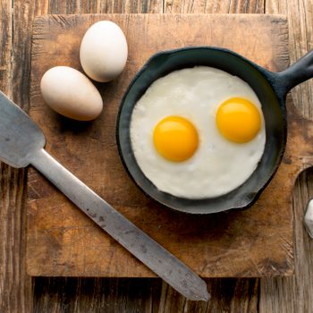 eggs in cast iron skillet on wood overhead