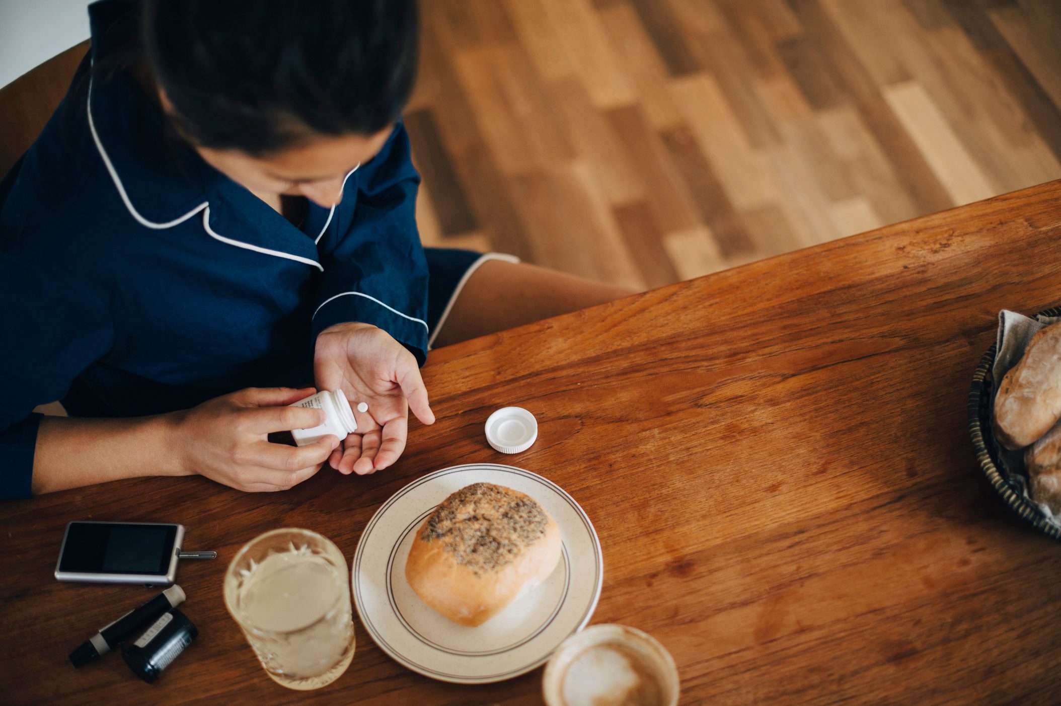 High angle view of woman taking medicine while having breakfast at table