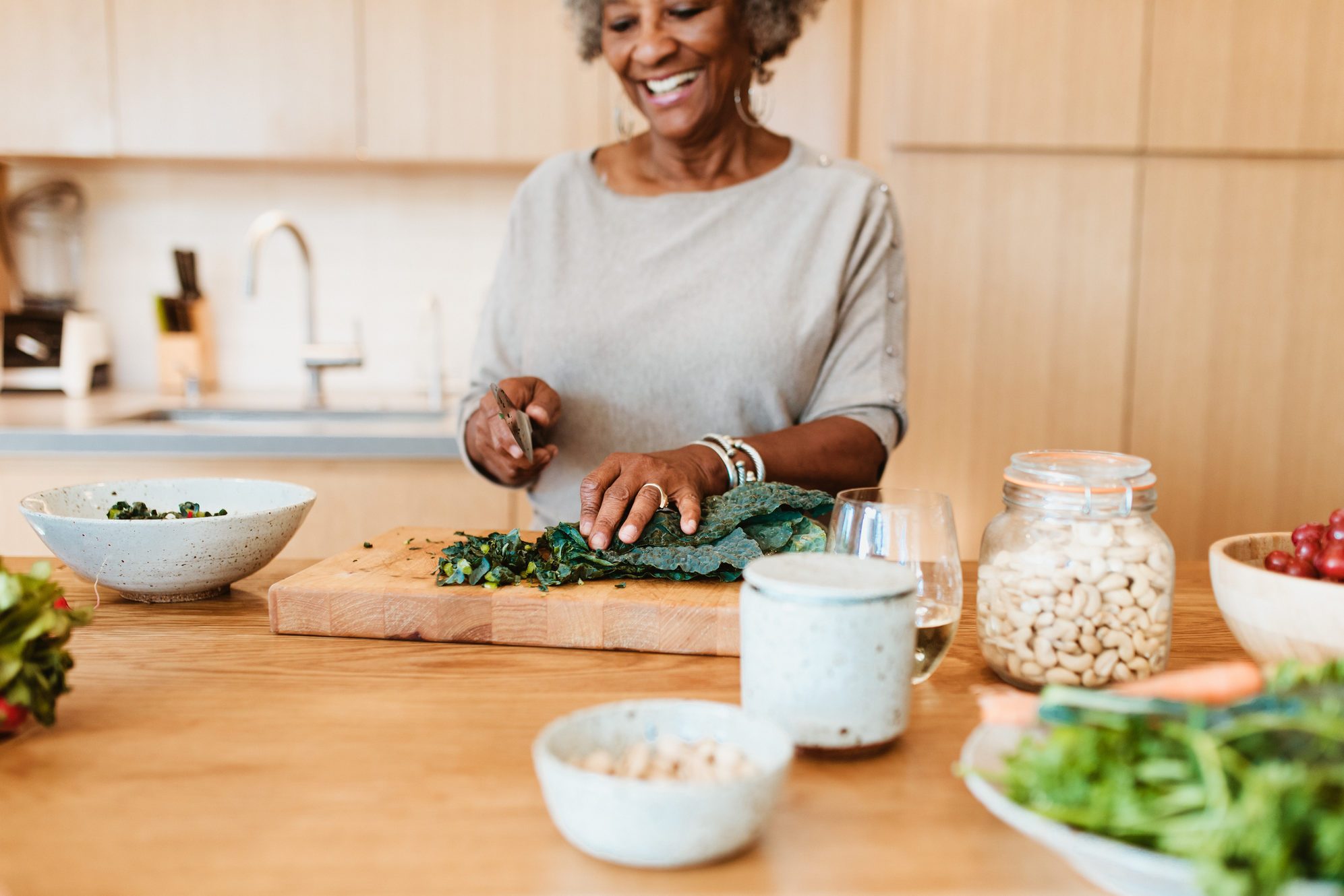 Senior female chopping vegetable at kitchen island