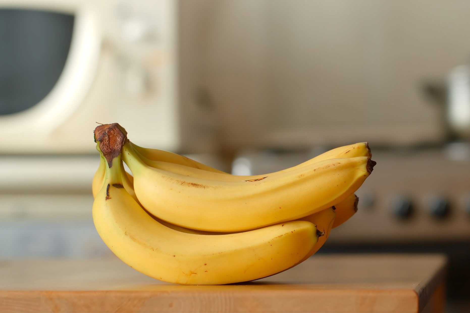 Bananas lie on a table in a kitchen