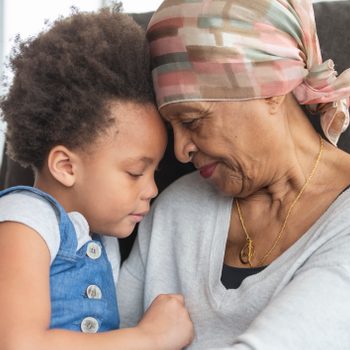 Senior woman with cancer lovingly holds granddaughter