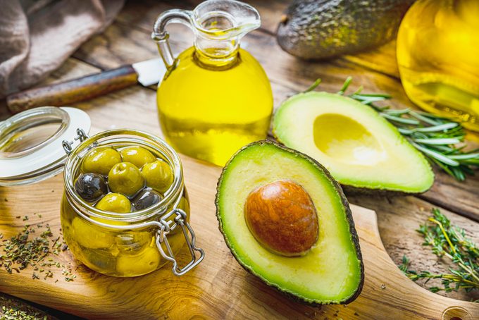 avocado, olives and olive oil on a wooden kitchen surface