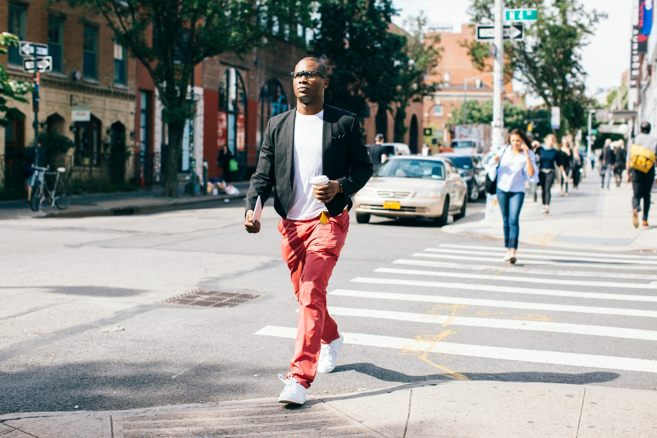 Man walking in the street, holding cup of coffee