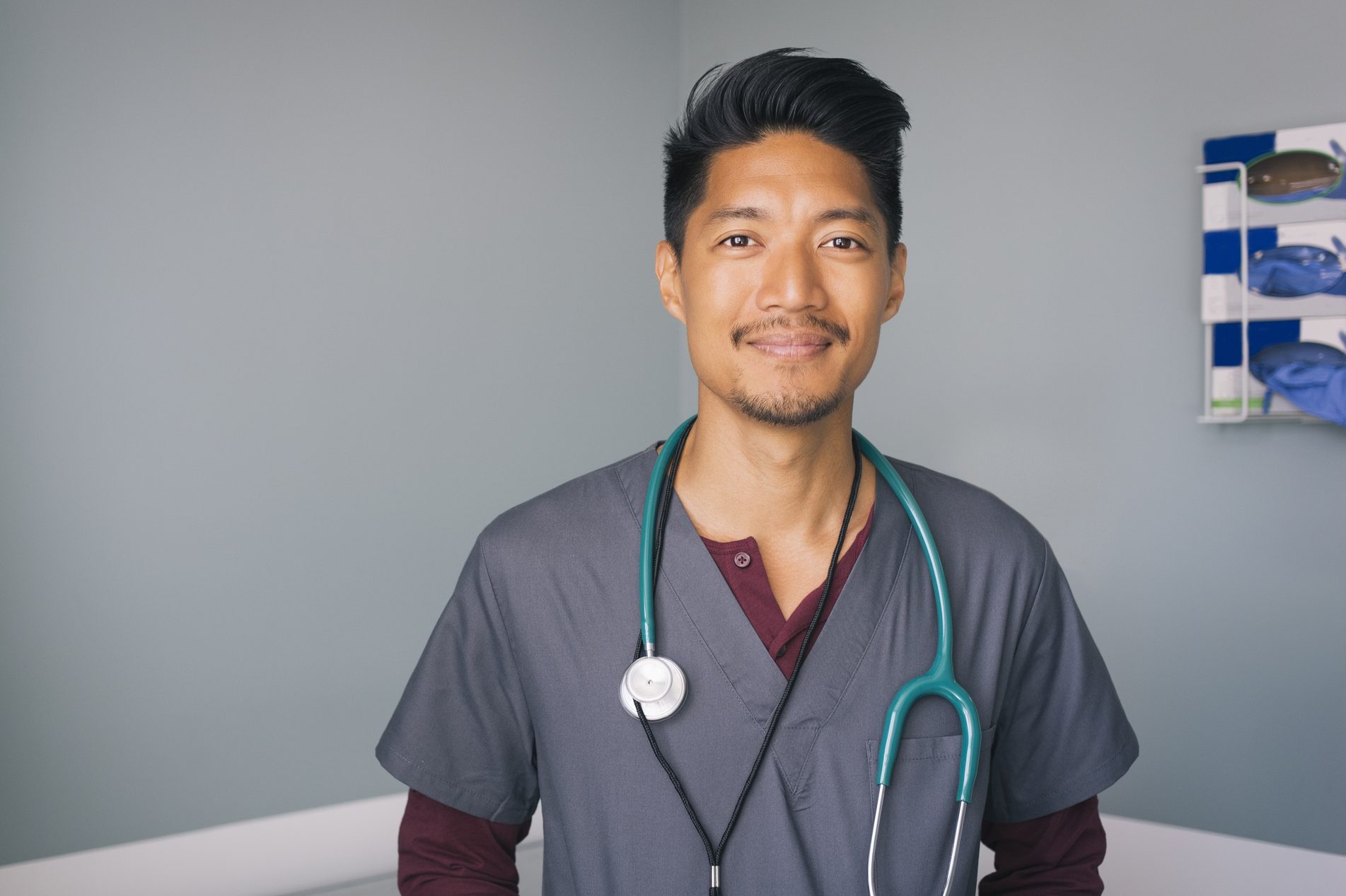 Portrait of nurse with stethoscope standing against wall in hospital