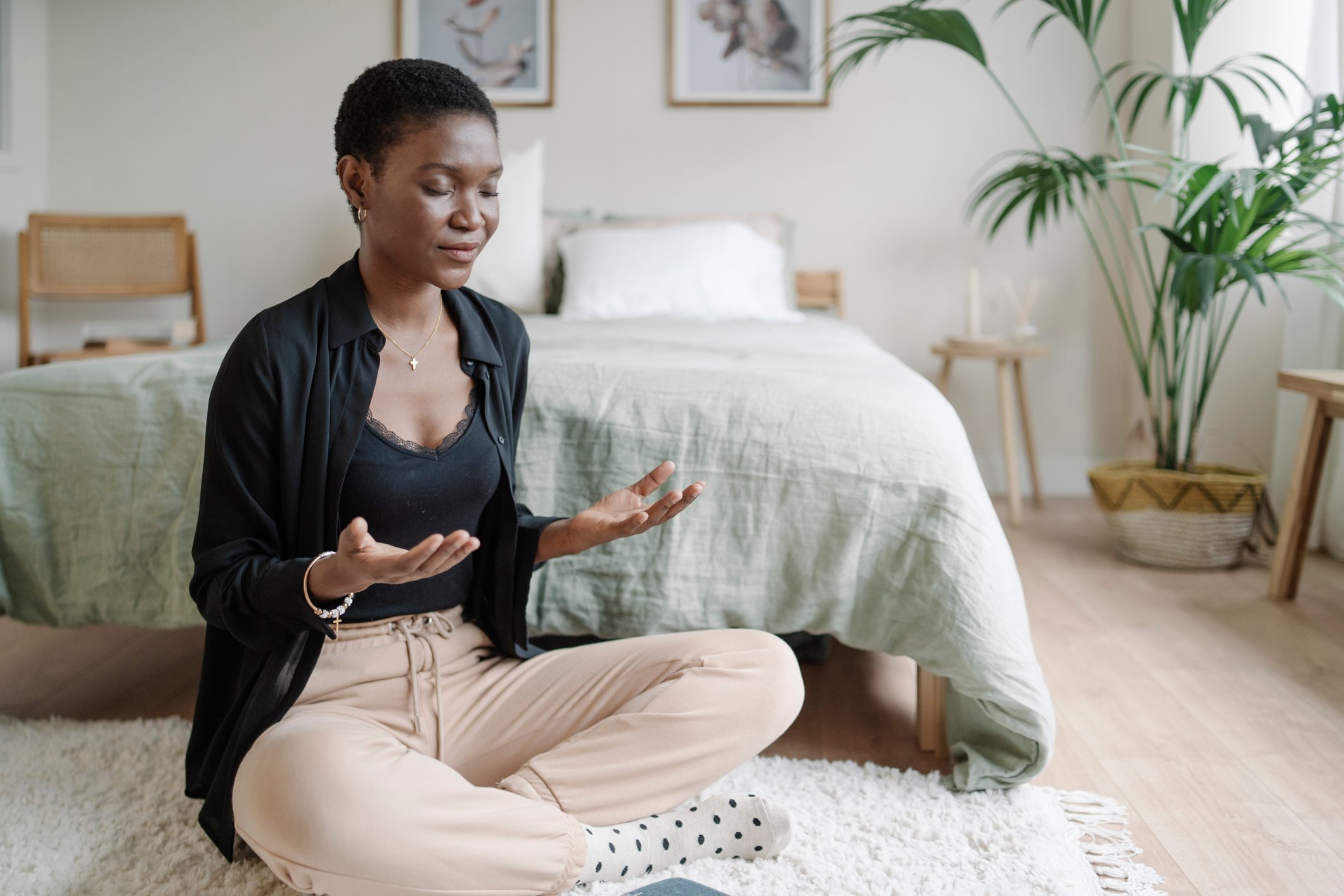 Relaxed woman sitting on the floor practicing meditation after reading book.