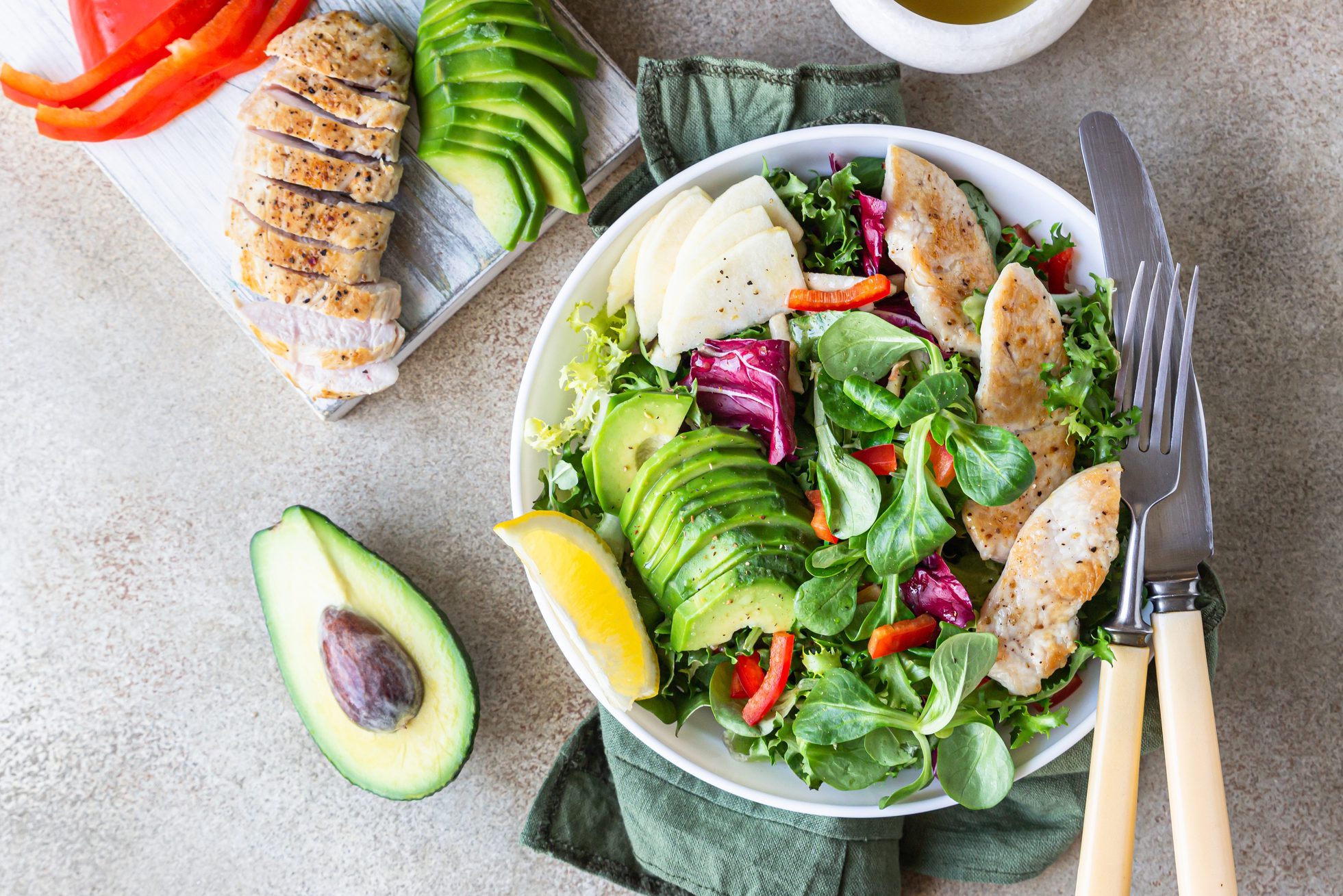 Avocado, apple, bell pepper and grilled chicken salad with ingredients for making salad. Paleo and keto diet. Top view.