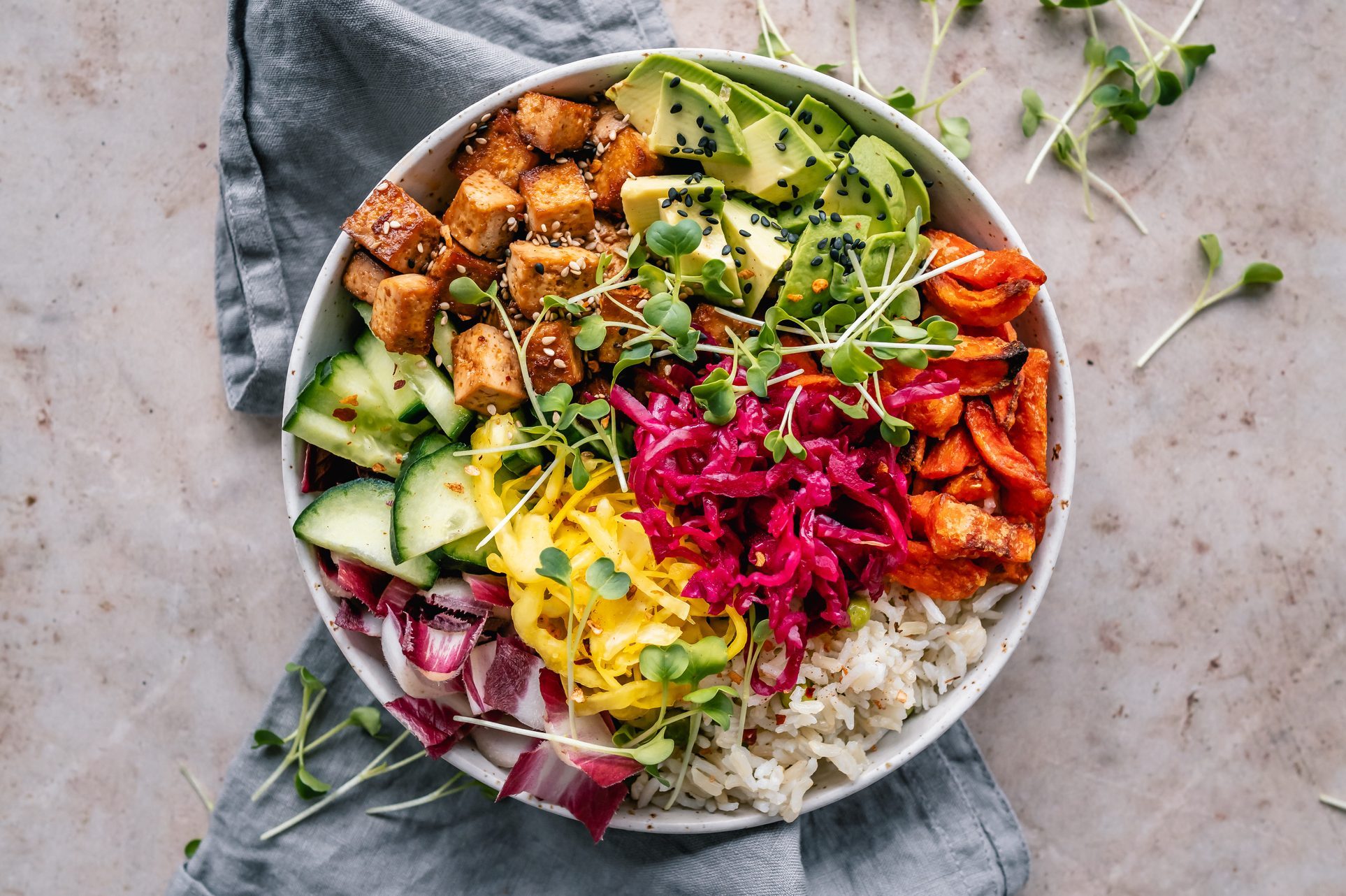 Buddha bowl with pan roasted tofu, avocado, sweet potato, rice, vegetables and mixed seeds