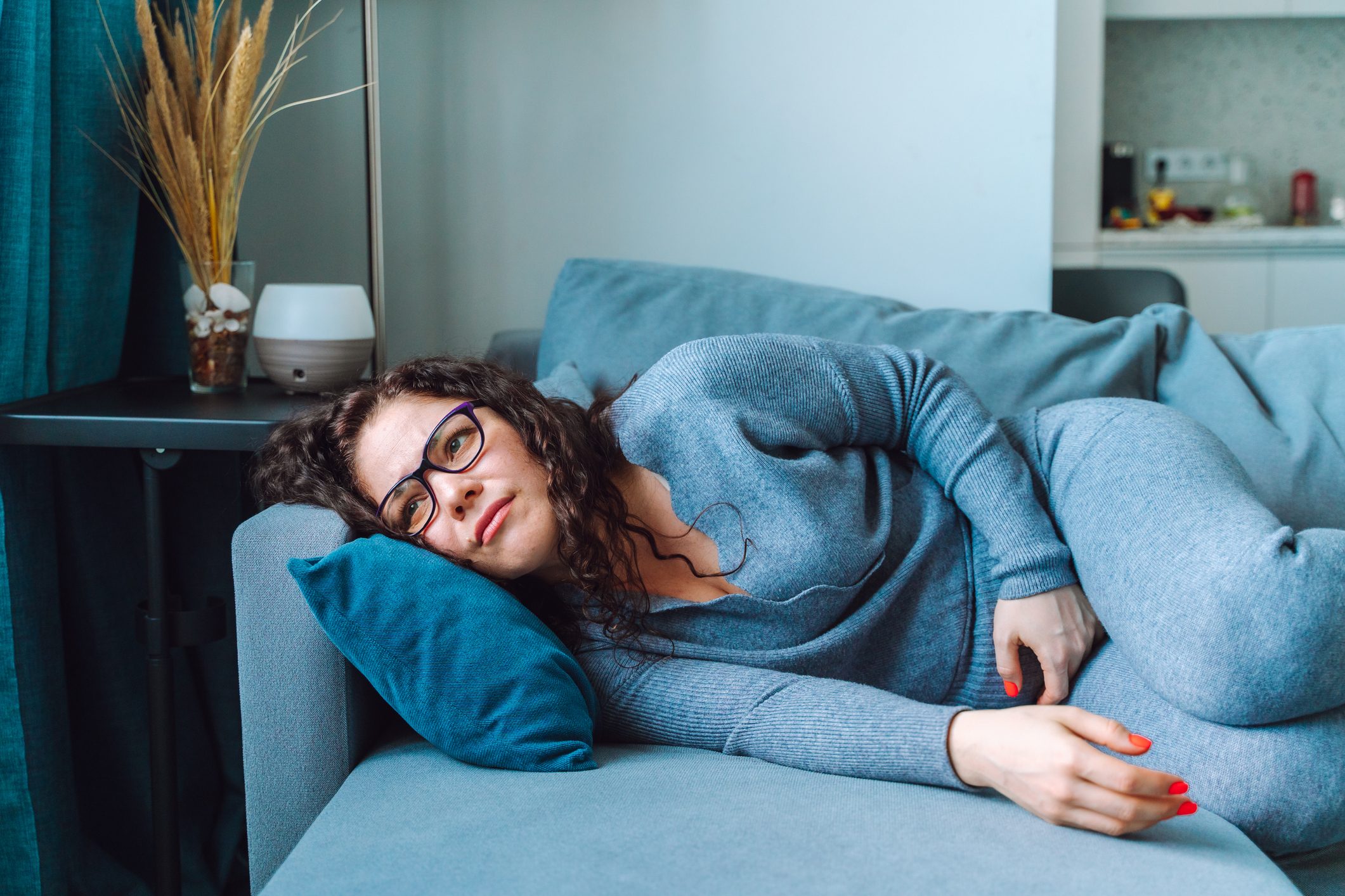 Middle age woman lying on sofa and feel abdomen pain