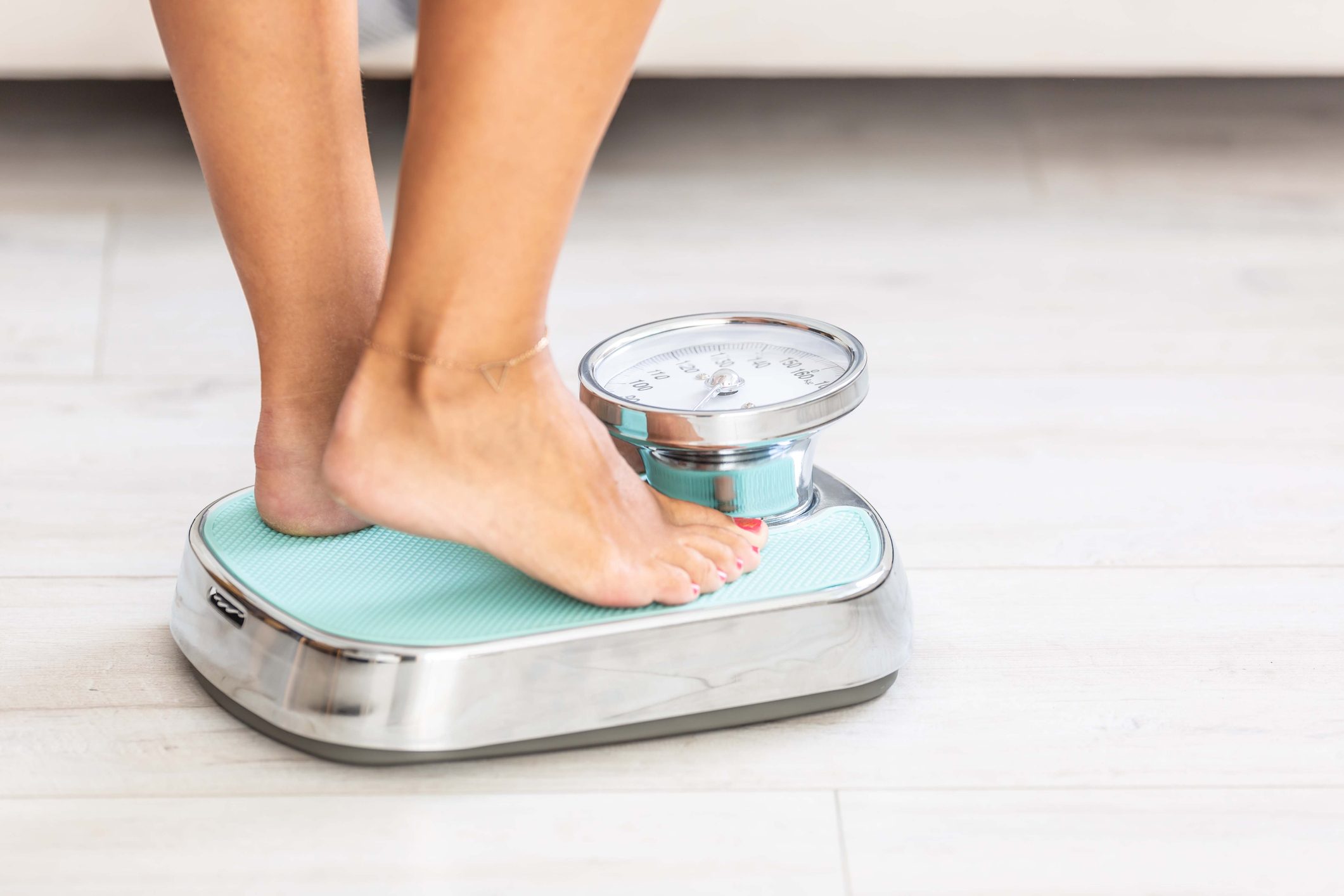 Woman standing on scale, close-up of legs.