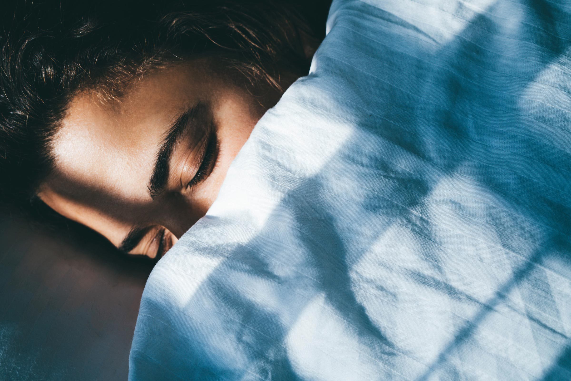 Lady sleeps in bed tossing turning in dream under blanket