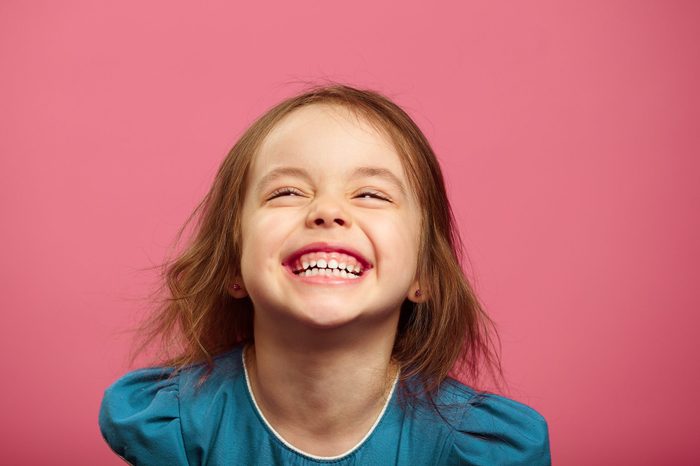 Joyful little girl sincere laughing at pink isolated background.