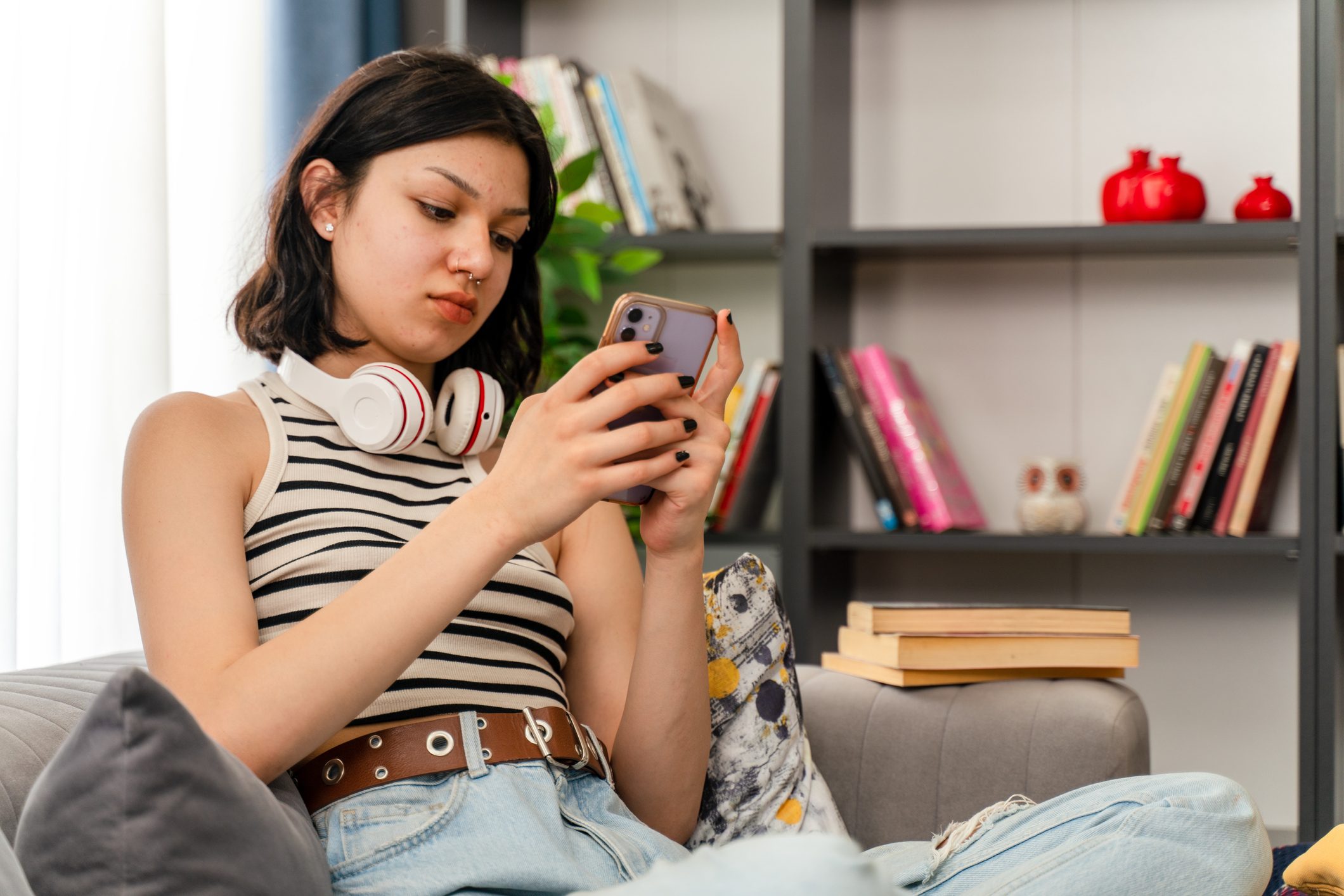 teen girl checking social media holding smartphone at home