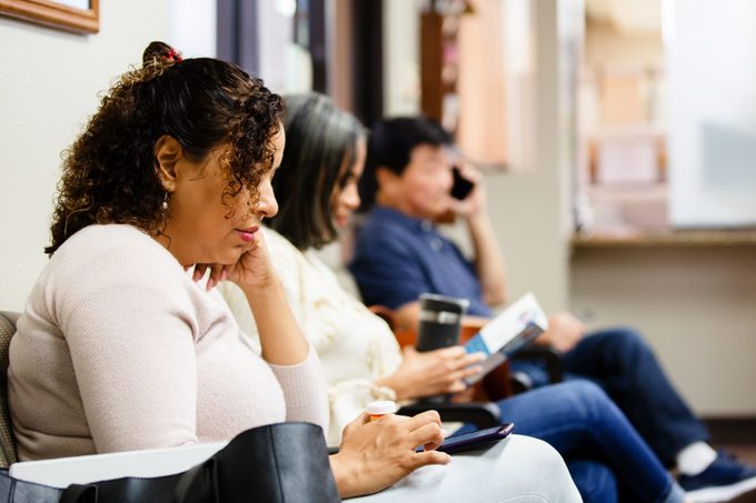 People look at brochure and use smart phones while waiting