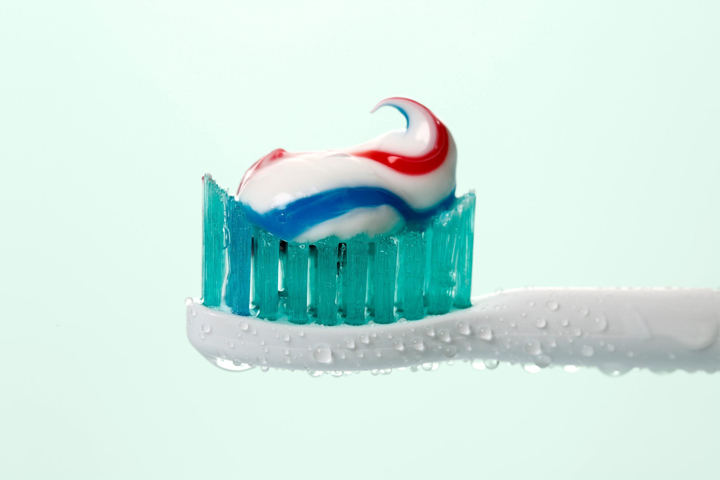 toothpaste of toothbrush on a mint green background