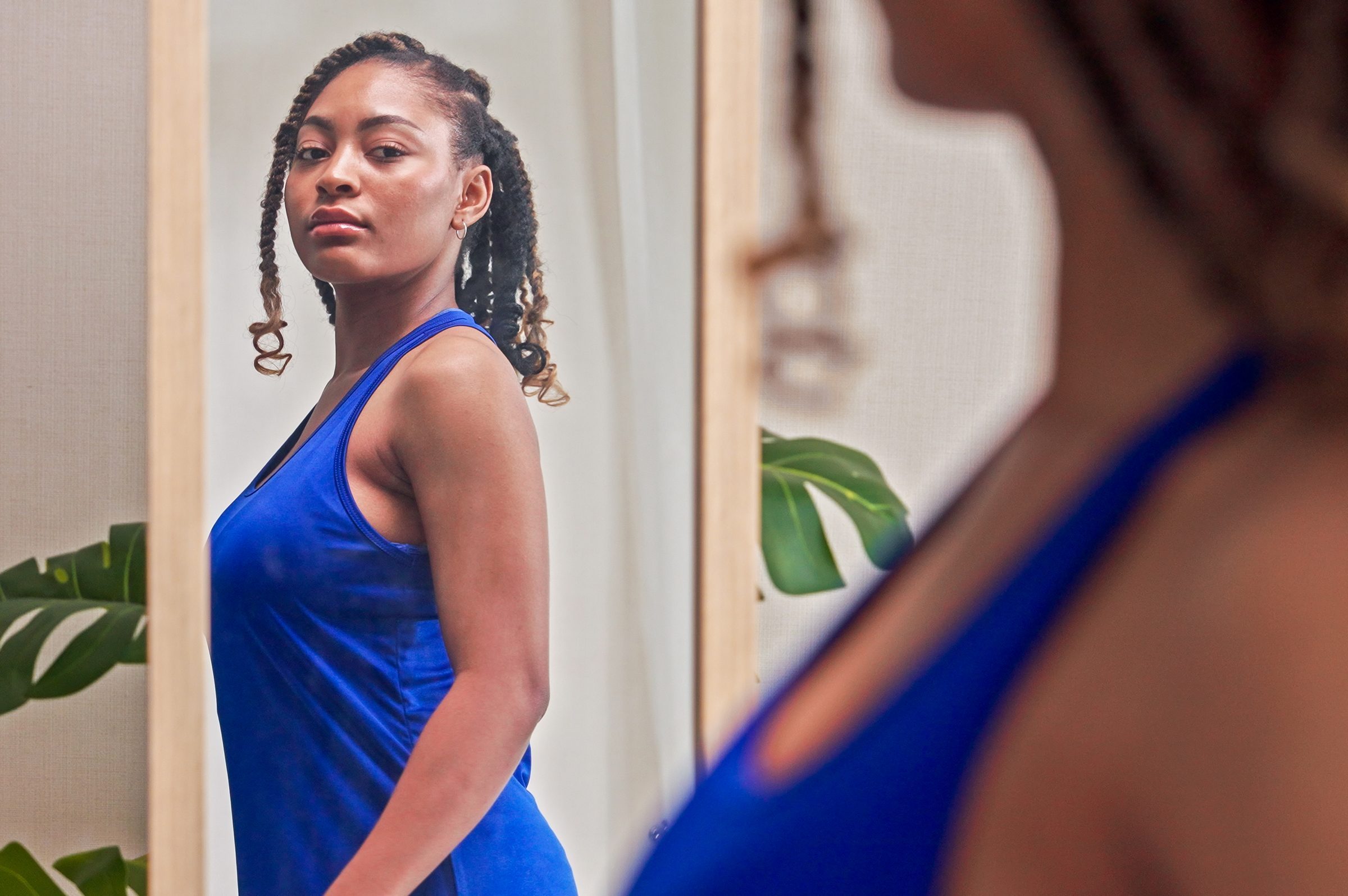 woman looking at herself in the mirror wearing a blue tank top