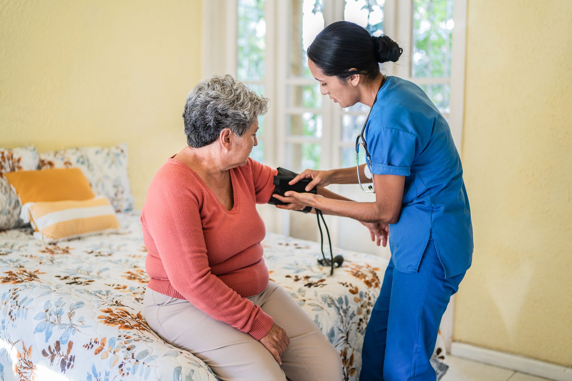 Nurse Measuring The Pressure Of Senior Woman In The Bedroom In A Nursing Home