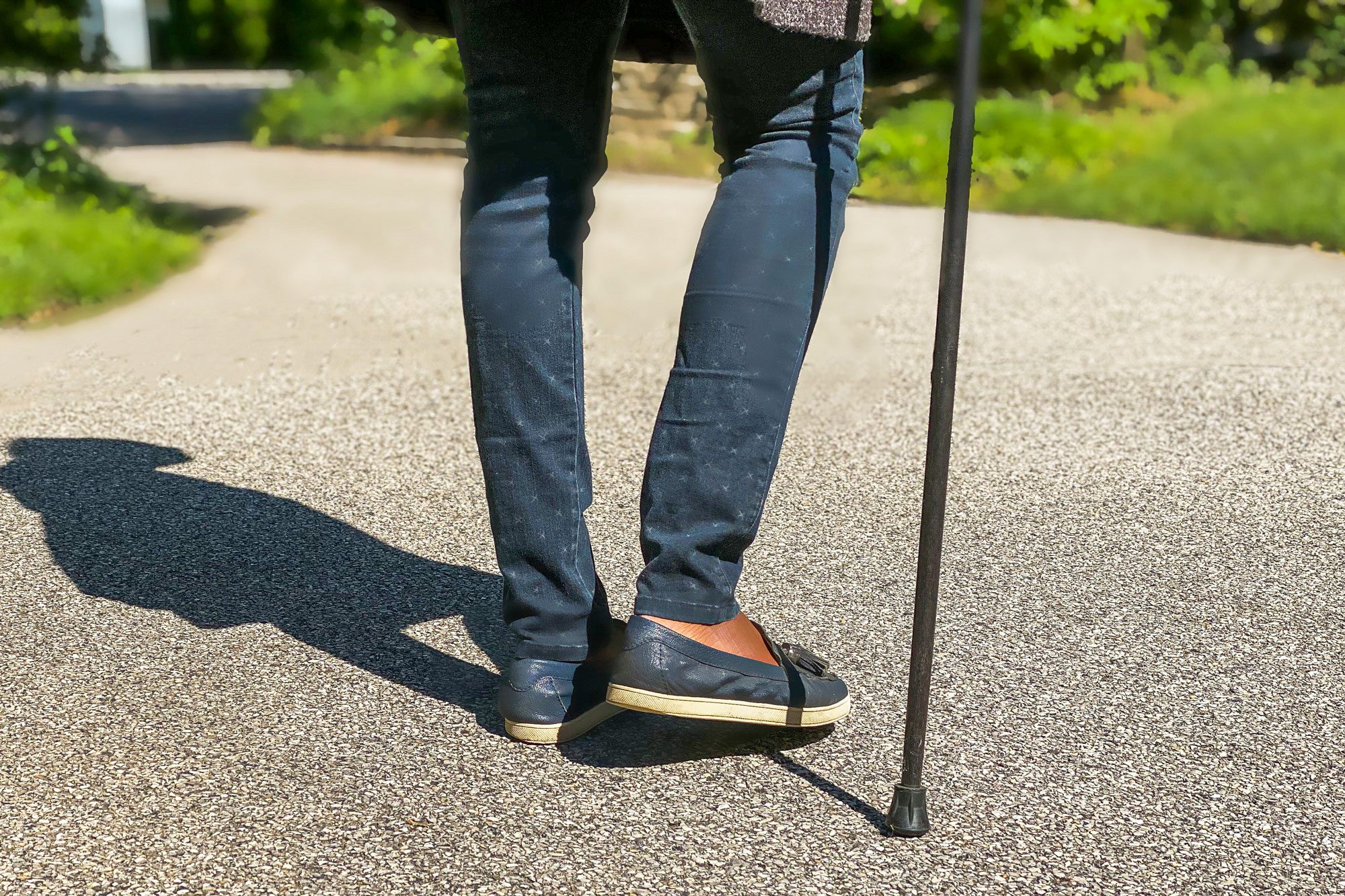 Woman Walking Outdoors With Assistance Of A Walking Cane