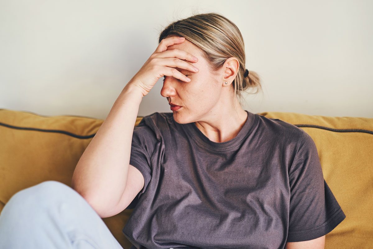 Woman Sitting On Couch With Her Head In Her Hands